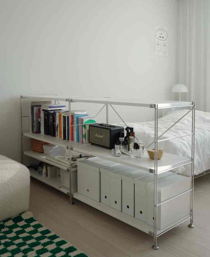 ホワイトトーンの寝室空間、無印良品のステンレス棚2台を連結し、空間仕切りと本や小物の収納が調和したシンプルなインテリア