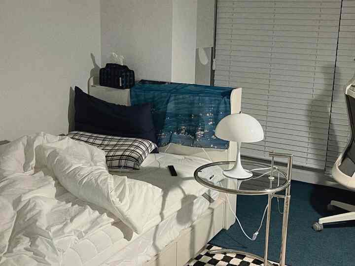 ホワイトとブルーのトーンが調和したミッドセンチュリーモダンな寝室、木製ブラインドとサイドテーブルが配置された落ち着いたインテリア