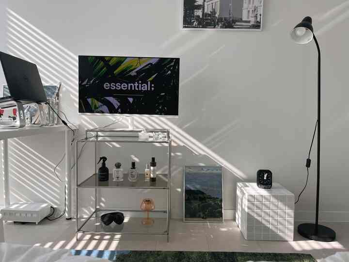 白と黒のトーンが調和したモダンなホームオフィス空間、メタリックシェルフや額縁、ノートパソコンとフロアランプが配置された印象的なインテリア