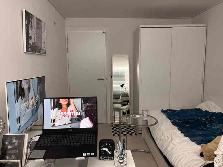 ホワイトとグレーのトーンでまとめられたコンパクトなモダンな一人暮らしの寝室、ベッド、全身鏡、サイドテーブルが配置された印象的な空間