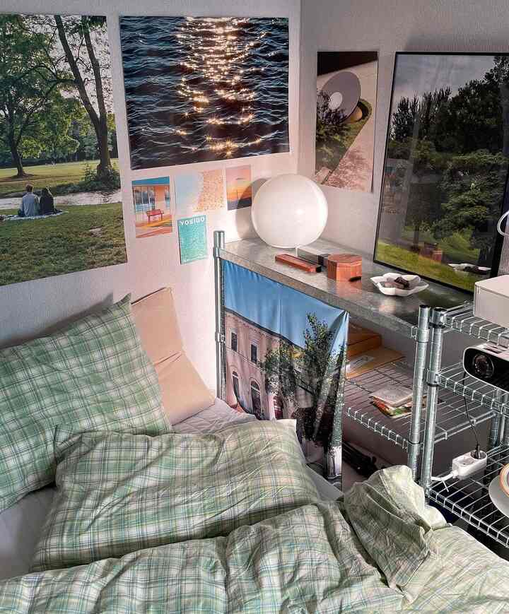 ナチュラルカラーの寝室、グリーンチェックの寝具と複数のポスターが壁に掛かる雰囲気のある空間