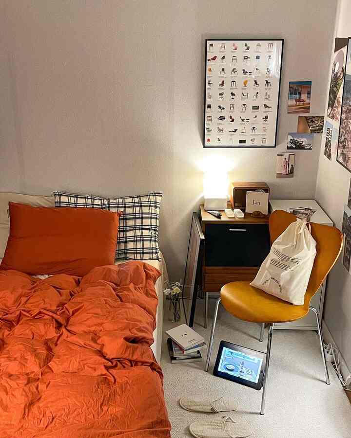 温かみのあるウッドトーンとオレンジの寝具が映える、整ったレイアウトの落ち着いた寝室インテリア