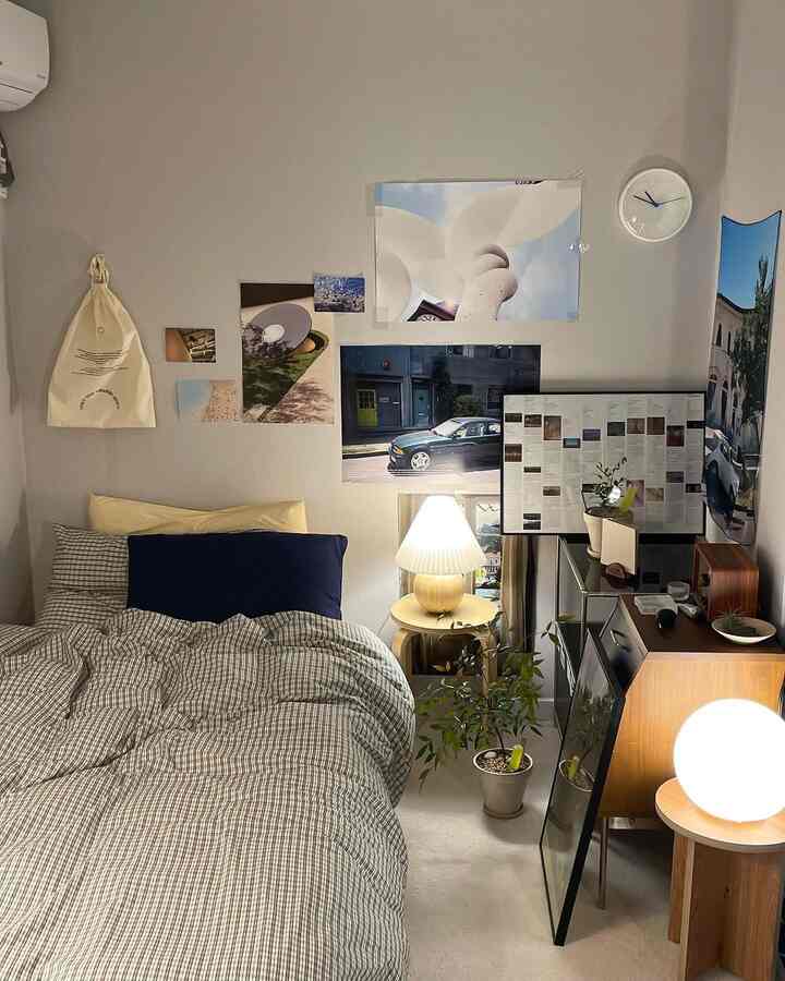 ナチュラルカラーの狭い寝室、チェックの寝具とサイドテーブル、多彩な壁のポスターと照明が調和した雰囲気のある空間