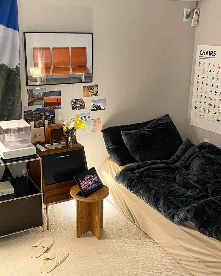 ダークな寝具とアイボリーのラグが配置された居心地の良い寝室、モダンな家具と壁の装飾が調和した雰囲気のあるインテリア