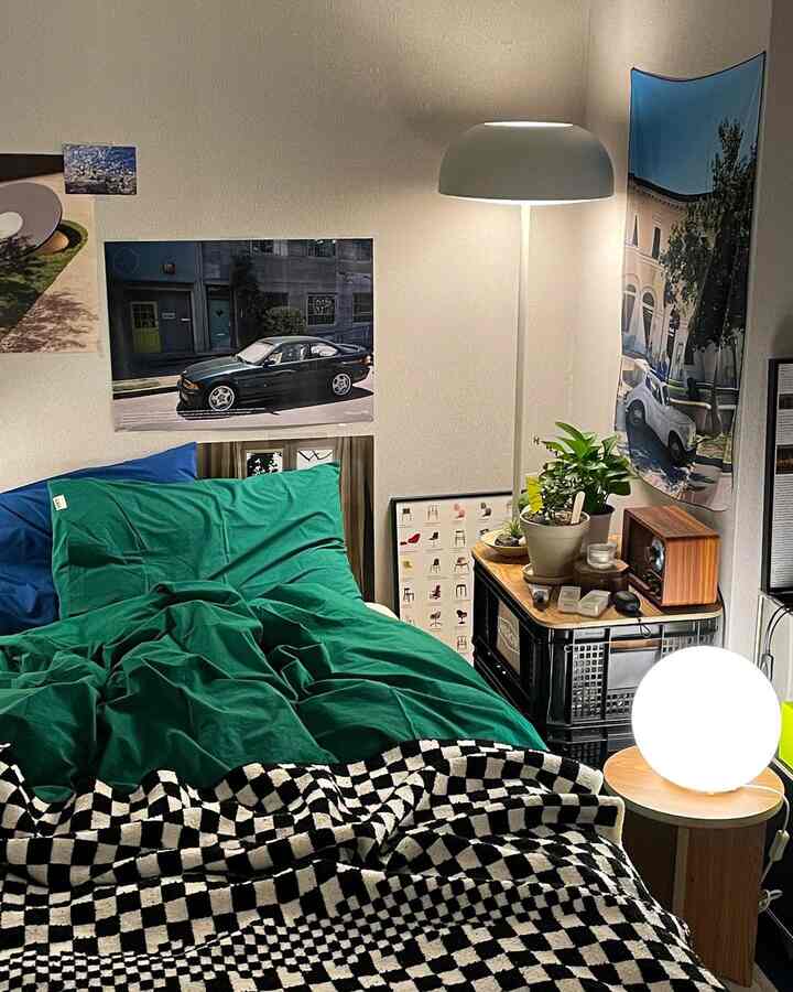 緑と青の寝具が配された寝室、ナイトテーブルとフロアランプが温かみのある雰囲気を醸し出す居心地の良い空間