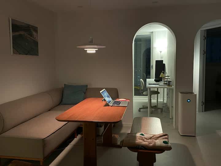 ナチュラルカラーのダイニングリビング、アーチ型の入り口とペンダントライトが配置されたシンプルでモダンな作業空間