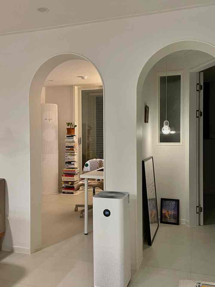 白色調のアーチ型の扉と空気清浄機が配置された、リビングとダイニングがつながるシンプルな雰囲気のインテリア
