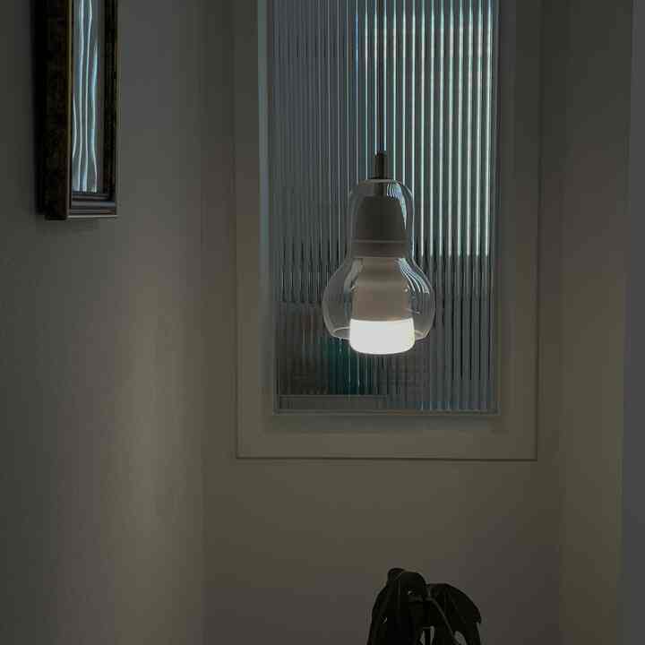 白いトーンの玄関、モル板ガラスの窓とポイント照明が配置された雰囲気のある空間