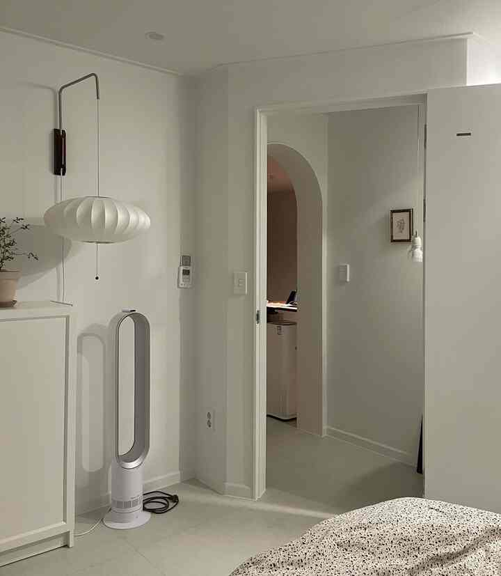 明るいホワイトトーンの寝室玄関スペース、アーチ型のドアウェイ、ダイソンのファン、ポイント照明が配置された清潔なモダンインテリア