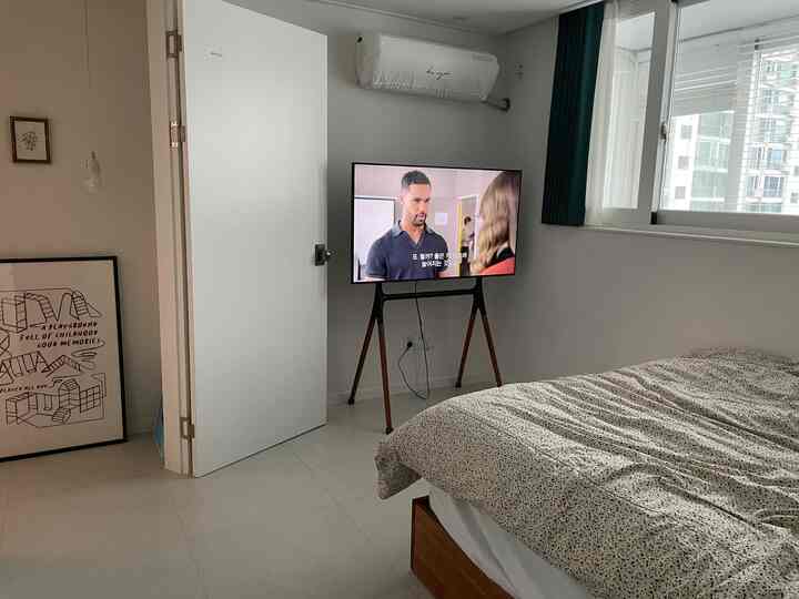 明るいホワイトトーンの壁にブラウンの木製家具が調和したコンパクトな寝室、シンプルで清潔感のある雰囲気のインテリア