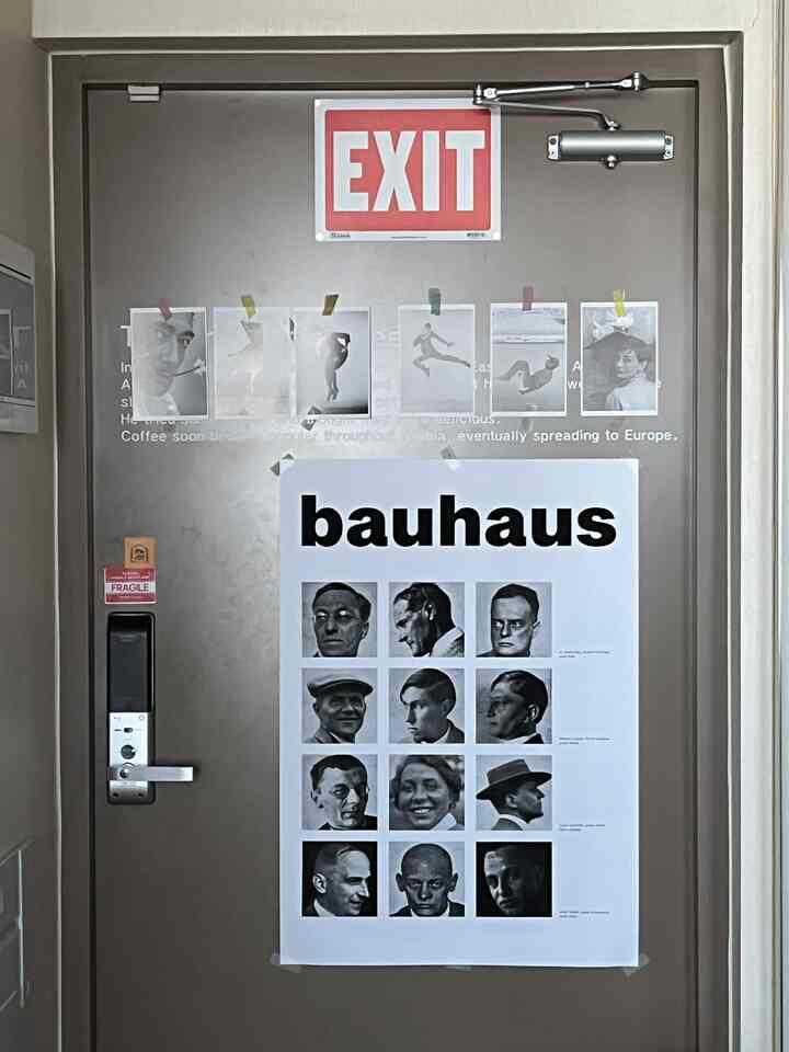 茶色の玄関ドアに大きなバウハウスポスターが配置されたモダンで清潔感のある印象的な空間