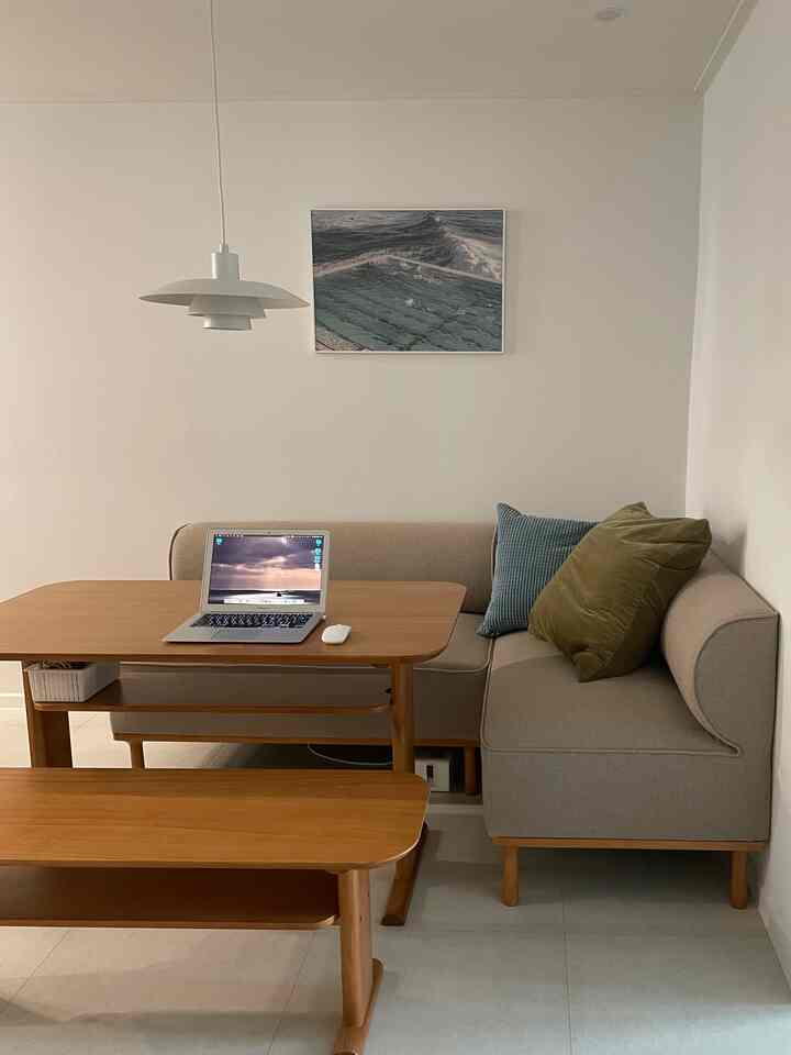 ナチュラルな木目調とベージュ色のダイニング、コーナーソファとダイニングテーブルが配置された落ち着いたシンプルな空間