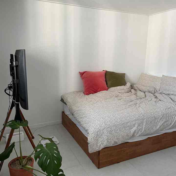 白い壁と茶色いベッドフレームの寝室、すっきりとした自然な雰囲気