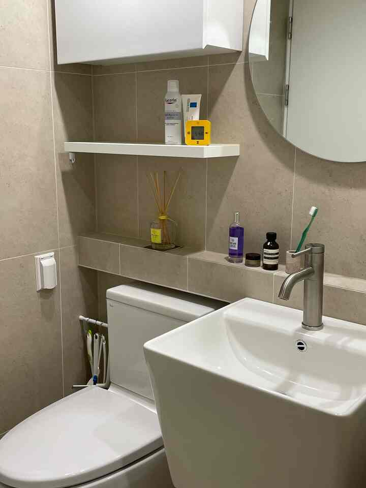 白とベージュのトーンのバスルーム、トイレ上の棚とマットな水栓が配置された清潔感のある空間