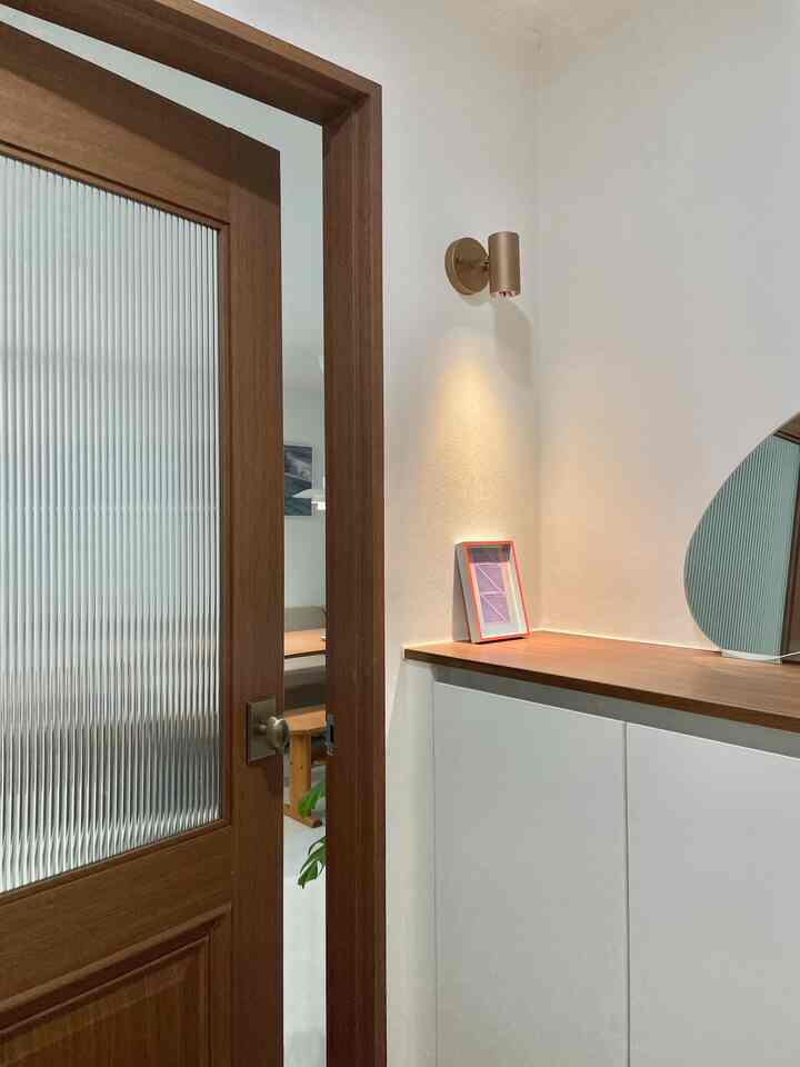 木目調とホワイトの玄関空間、木製の扉とシューズラックが温かみのあるシンプルで整った雰囲気を演出