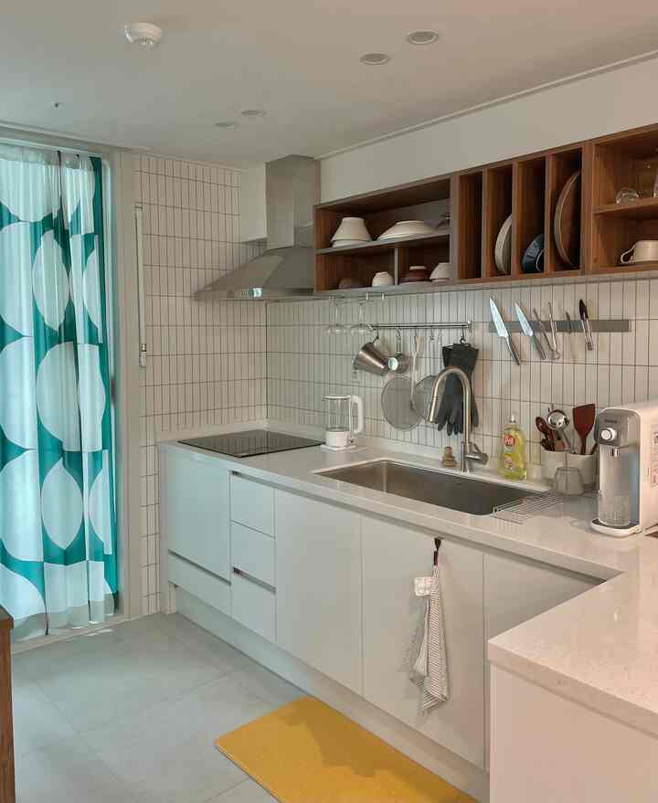 白と木目調のキッチンスペース、整然とした収納棚と調理器具が配された実用的なインテリア