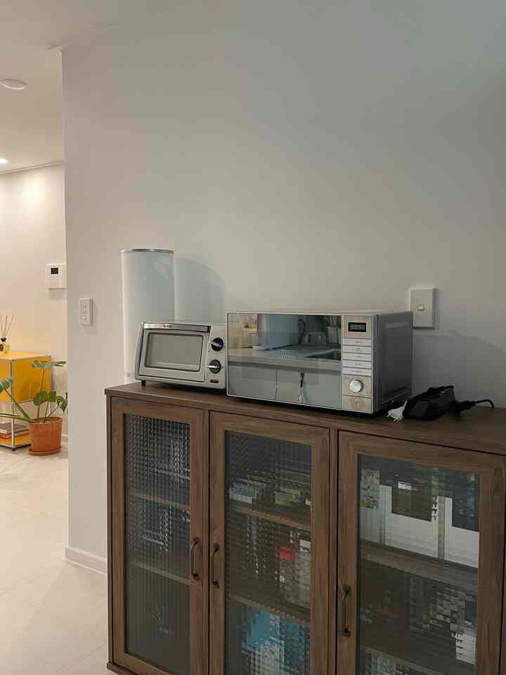 木目調のキャビネットの上に電子レンジとトースターオーブンが置かれたキッチンの空間