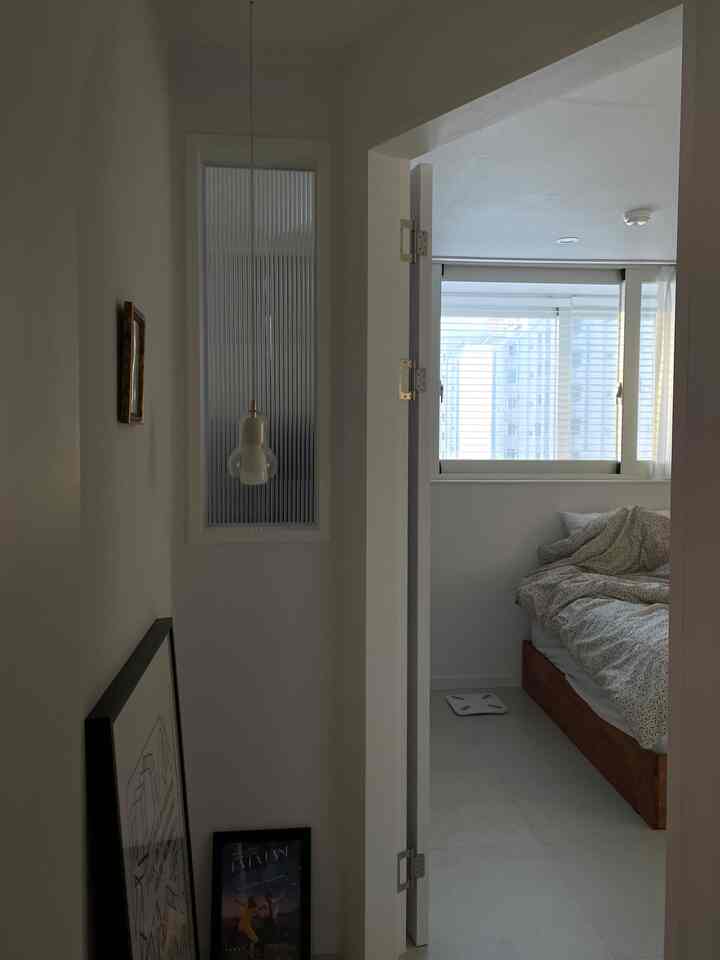 白と木目調が調和するコンパクトな寝室と玄関、模様入りガラスとペンダントライトが印象的な落ち着いた空間