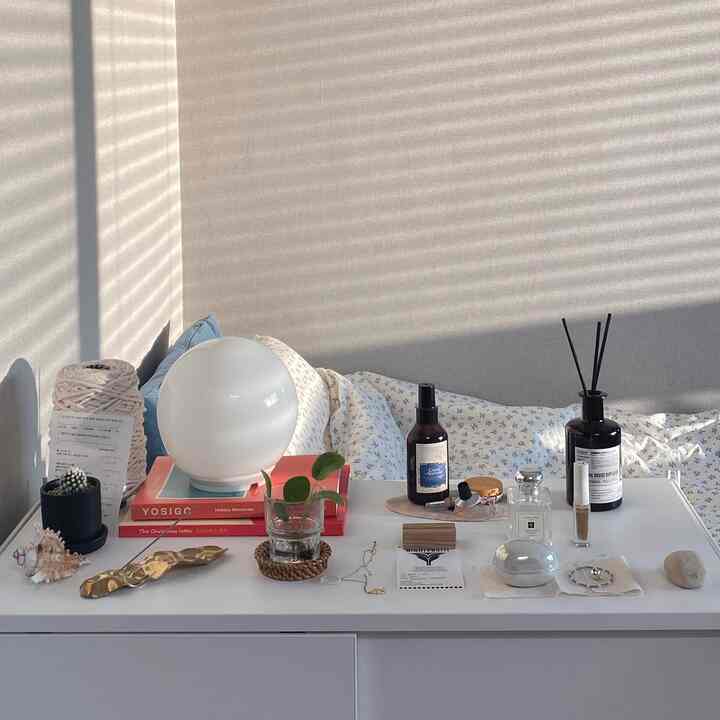 暖かいナチュラルカラーのワンルーム寝室、白い棚に小物や照明が配置された雰囲気のあるインテリア