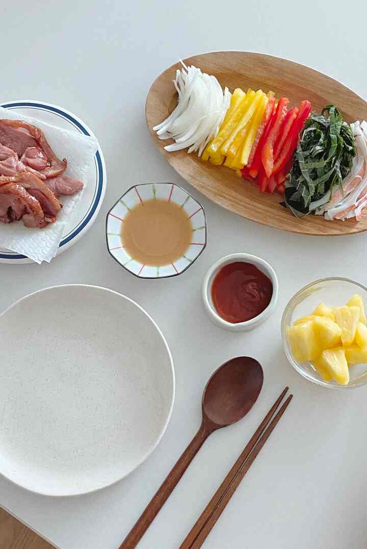 ナチュラルな木調と白を基調としたダイニングテーブルにカトラリーセットとカラフルな野菜が配された素朴な食卓のインテリア