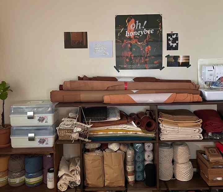 ベージュとブラウンの自然な色調の収納スペースと素材が揃ったキッチンの壁面、各種制作道具とミシンが配置された雰囲気のある作業スペース