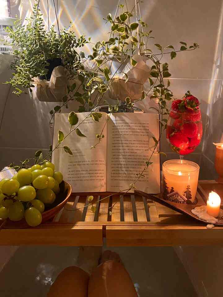 暖かい木目調と白い背景の浴槽空間、キャンドルとイチゴ入りワイングラス、新鮮な緑の植物が落ち着いた雰囲気を演出しています。