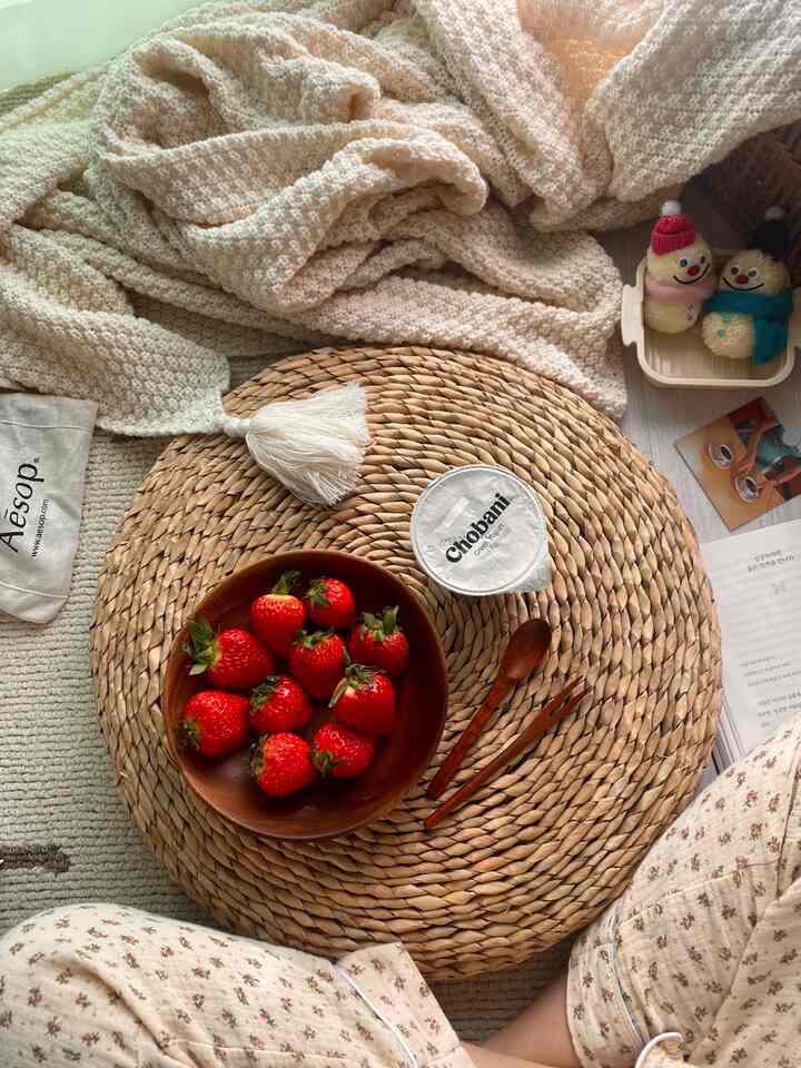 ベージュとナチュラルウッドトーンのラタンクッションに苺とヨーグルトが置かれた雰囲気のあるインテリア