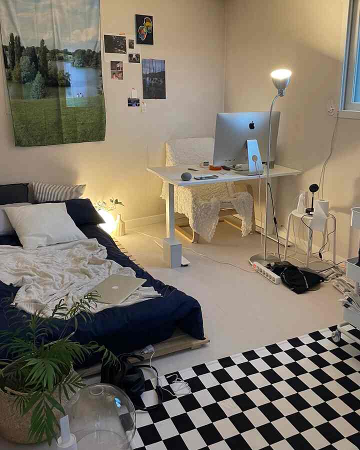 ベージュ色の壁と木製ベッドフレームがある一人暮らし用寝室、シンプルモダンなスタイルでデスクとアームチェアが配置された空間