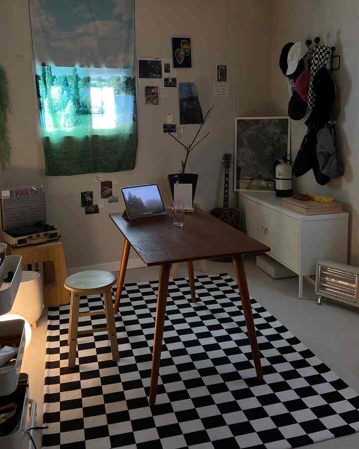 白と黒の調和が取れたコンパクトなダイニング、木製テーブルとスツール、チェック柄のラグが配置されたミニマルでモダンなインテリア