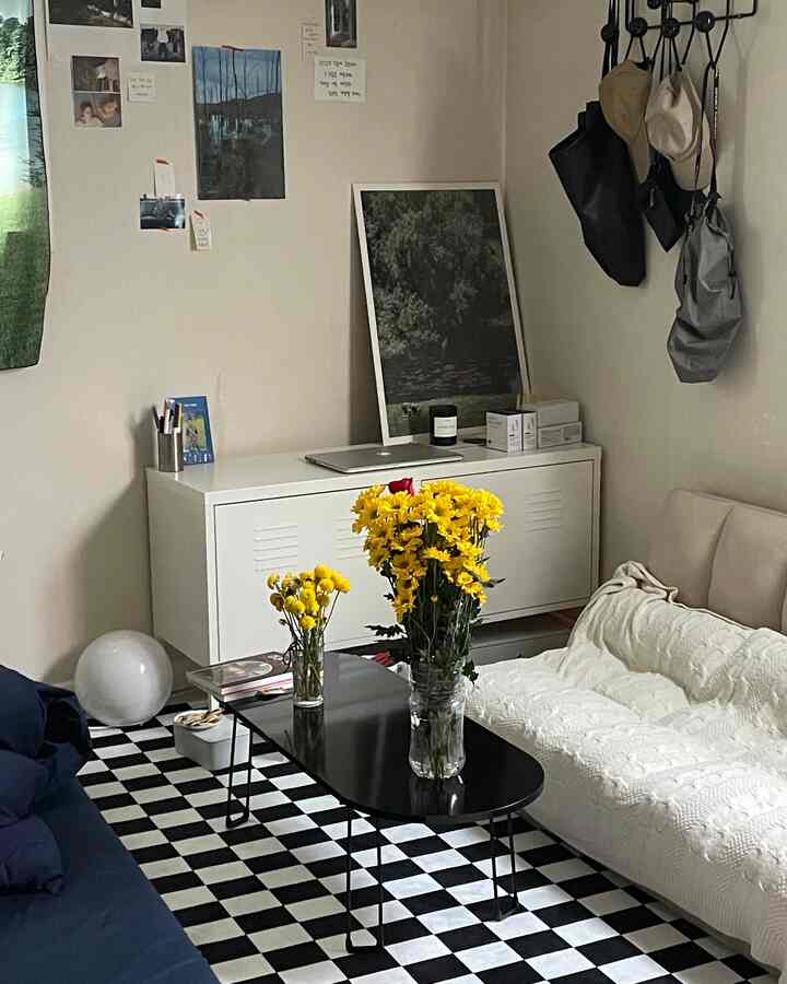 白と黒の調和が美しいリビング、中央に置かれた黒のコーヒーテーブルに黄色い花瓶が並び、二つのソファが配置された雰囲気のあるインテリア