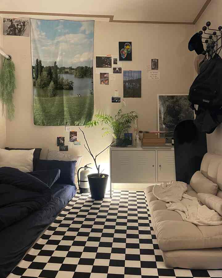 ベージュとネイビーの色調のワンルームリビング、2つのソファとチェッカーボードラグ、植物が配置された落ち着いた空間