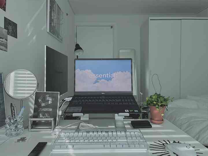 明るいホワイトトーンの小さな寝室兼ホームオフィス、机の上にノートパソコンと植物が配置されたシンプルなインテリア