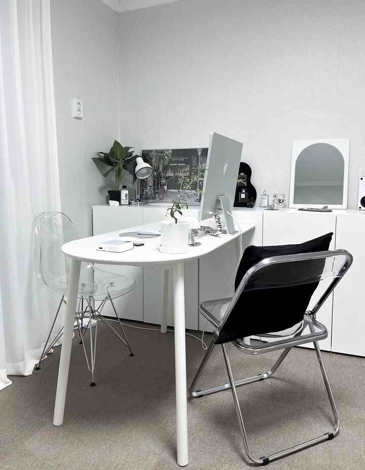 ホワイトと透明素材が調和するシンプルモダンなホームオフィス、白いデスクと2つの透明な椅子、収納キャビネットとカーテンが配置された空間