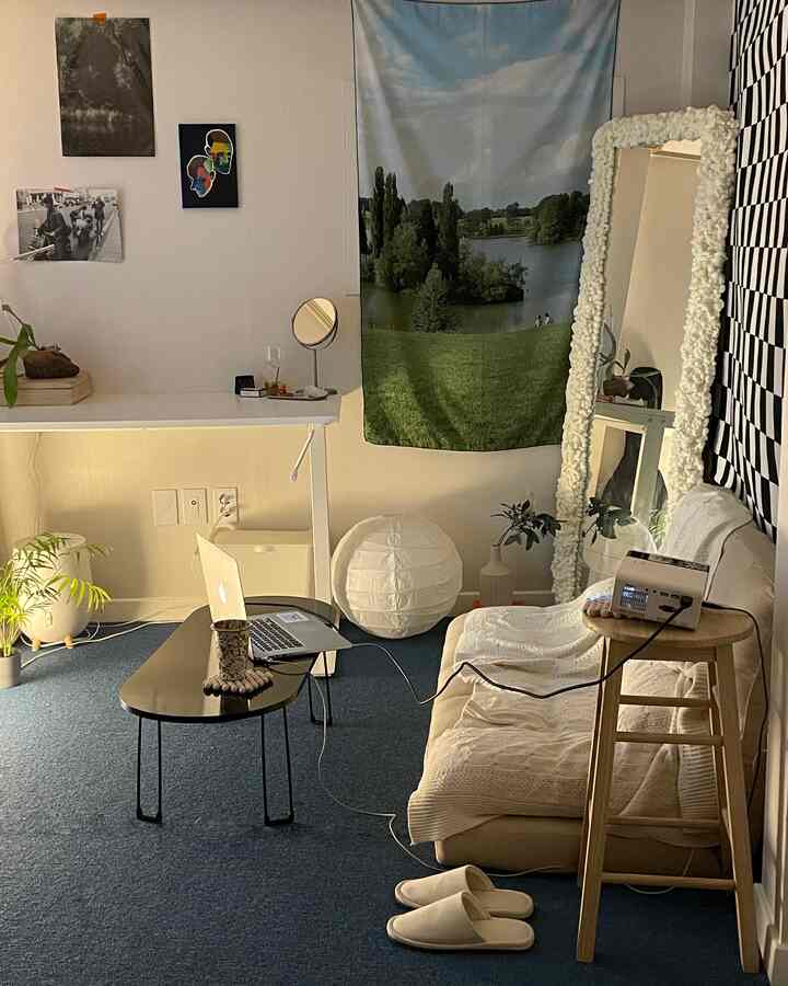 ナチュラルカラーの北欧風ワンルームリビング、ソファやコーヒーテーブル、大きな鏡、壁のアートが配置された落ち着いた空間