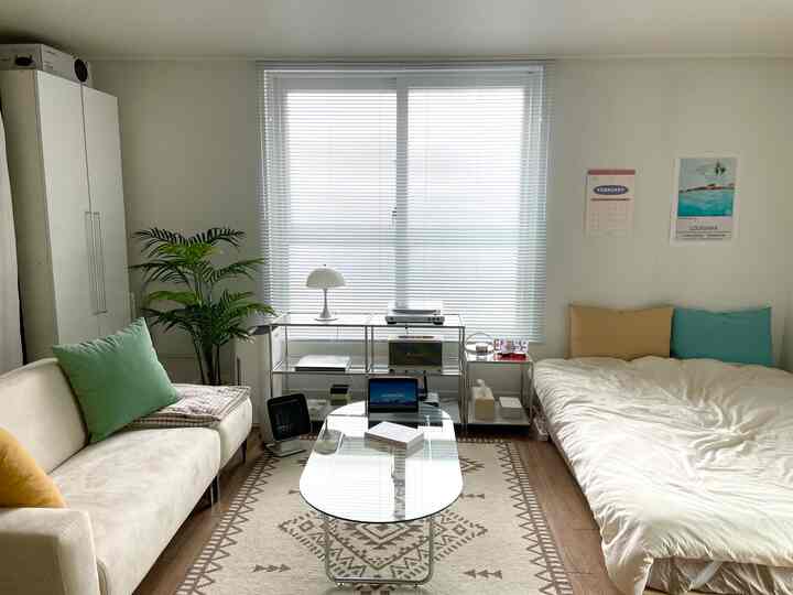 ホワイトとベージュの色調の寝室、ミッドセンチュリーモダンのソファとベッドが調和した印象的な空間