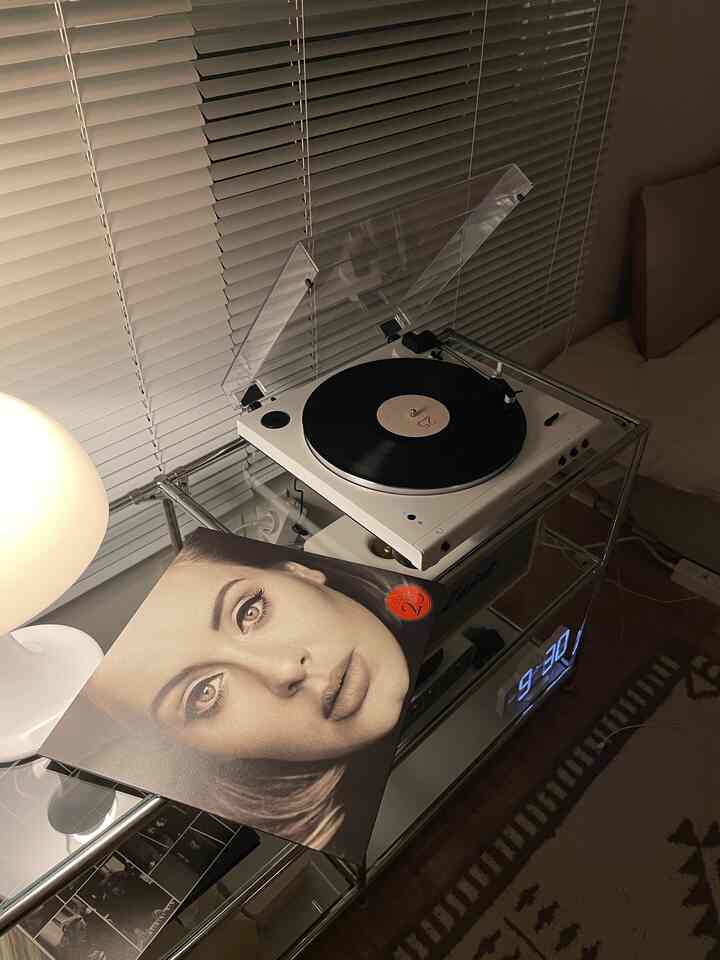 白を基調としたリビング、透明な棚に白いターンテーブルとアデルのLPレコードが置かれた雰囲気のあるレトロなインテリア