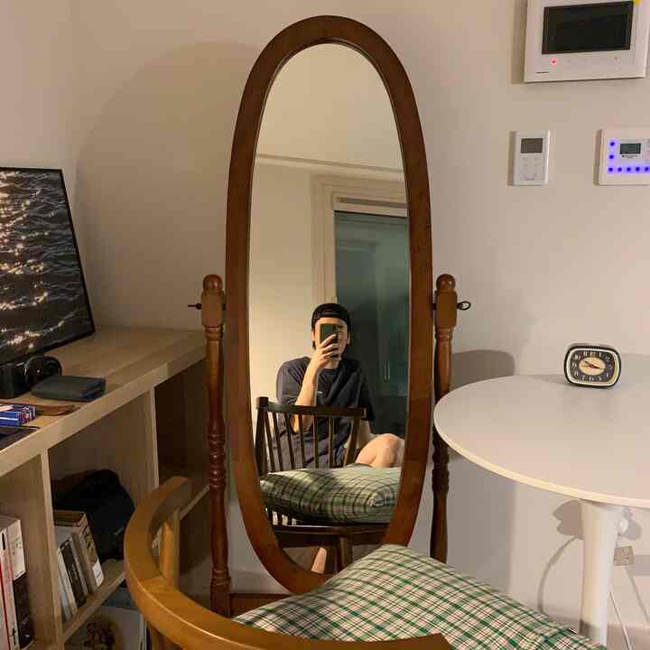 温かみのある木目調とレトロな雰囲気の一人暮らし空間、木製全身鏡とチェック柄クッションが配置された印象的なインテリア