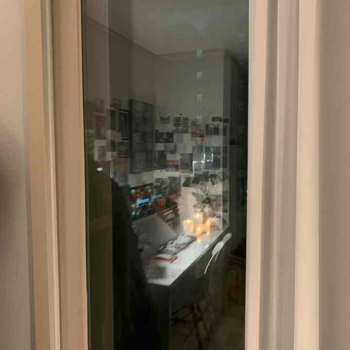 白を基調としたバルコニーのホームオフィス、長いデスクとカーテン、写真が飾られた壁が配置された集中できる空間