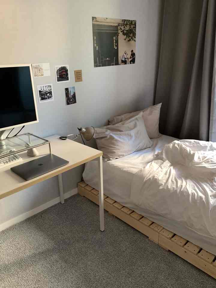 ホワイトとナチュラルウッド調が調和するモダンなワンルーム、デスクとベッドが配置された清潔感のある空間