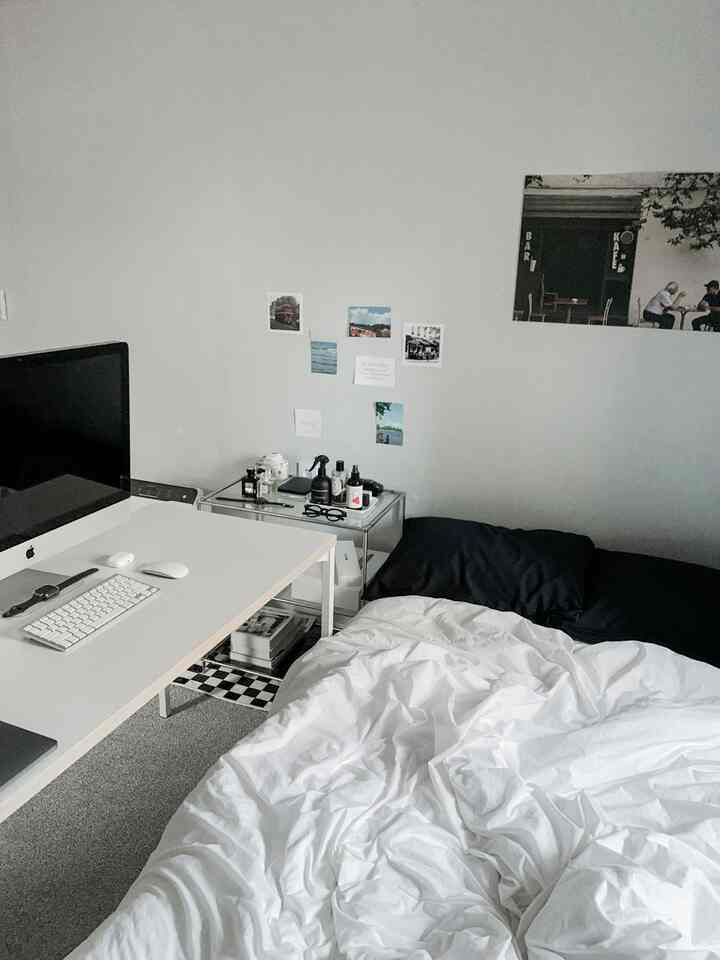 白と黒のトーンが特徴のモダンなワンルームの寝室兼ホームオフィス、デスクとベッドが近くに配置された印象的な空間