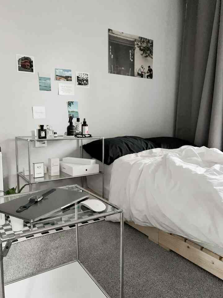 モノトーン調のワンルーム寝室、モジュールサイドテーブルと透明なデスクが配置されたモダンで洗練されたインテリア