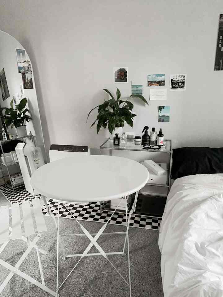 ホワイトとモノトーンのトーンのワンルーム寝室、中心に丸いメタルテーブルとモジュール家具が配置されたモダンなインテリア