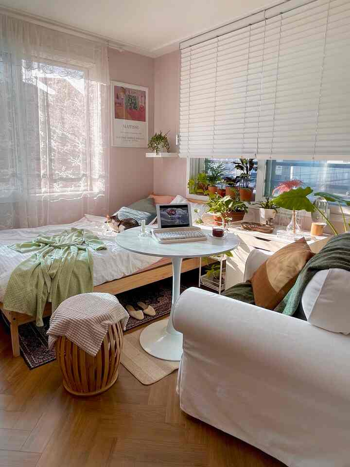 白と木目調の調和が美しい居心地の良い寝室、円形テーブルと植物が落ち着いた雰囲気を演出している