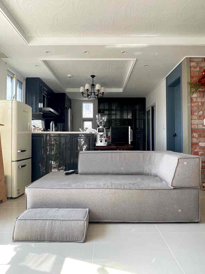 アイボリーのミニ冷蔵庫とグレーのソファが配置されたナチュラルカラーのリビングとキッチンの空間