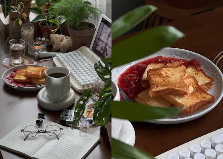 ブラウンの机の上にコーヒーとトースト、植物、白いキーボードが配置された落ち着いたおうちカフェの空間