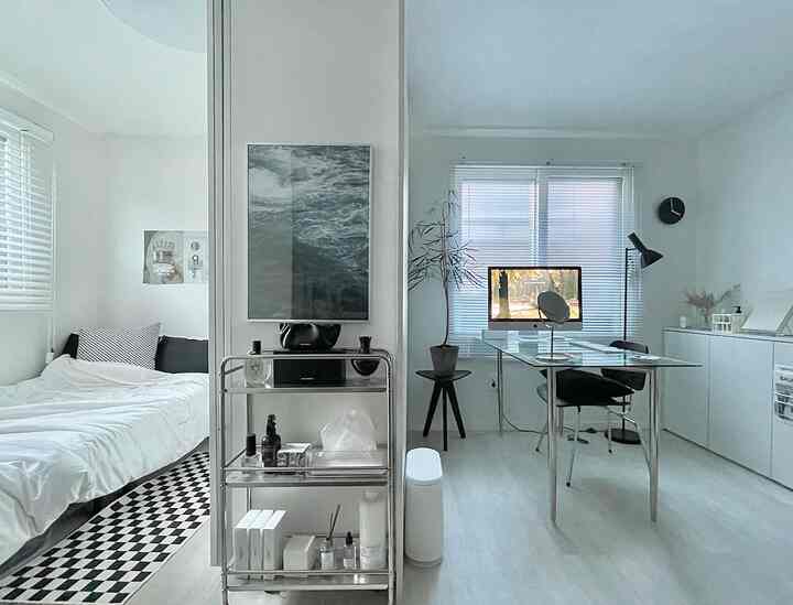 クールトーンの一人暮らし空間、左側に寝室、右側にガラステーブルとデスクが配置されたシンプルモダンなインテリア