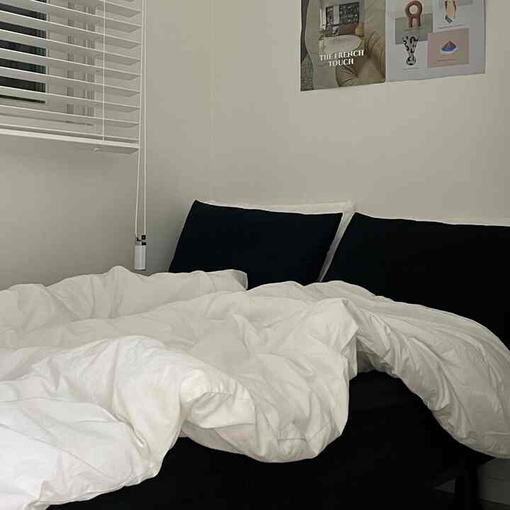 黒と白のトーンの寝室、黒いマットレスカバーと白い布団カバーが調和するシンプルな空間