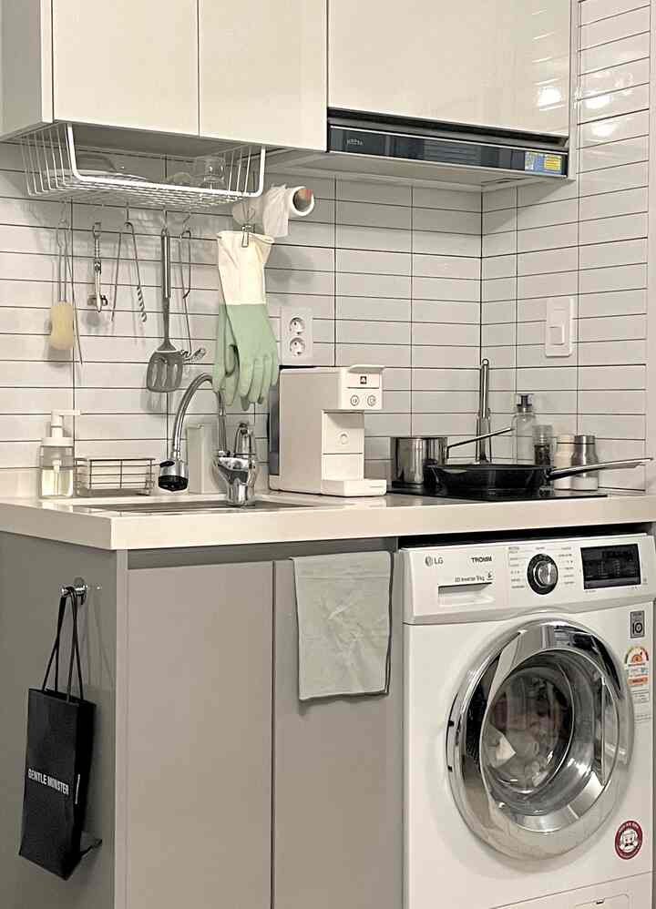 ホワイトとグレーのトーンの小さなキッチン、ステンレス調理器具とシンクが配置された清潔感のある空間