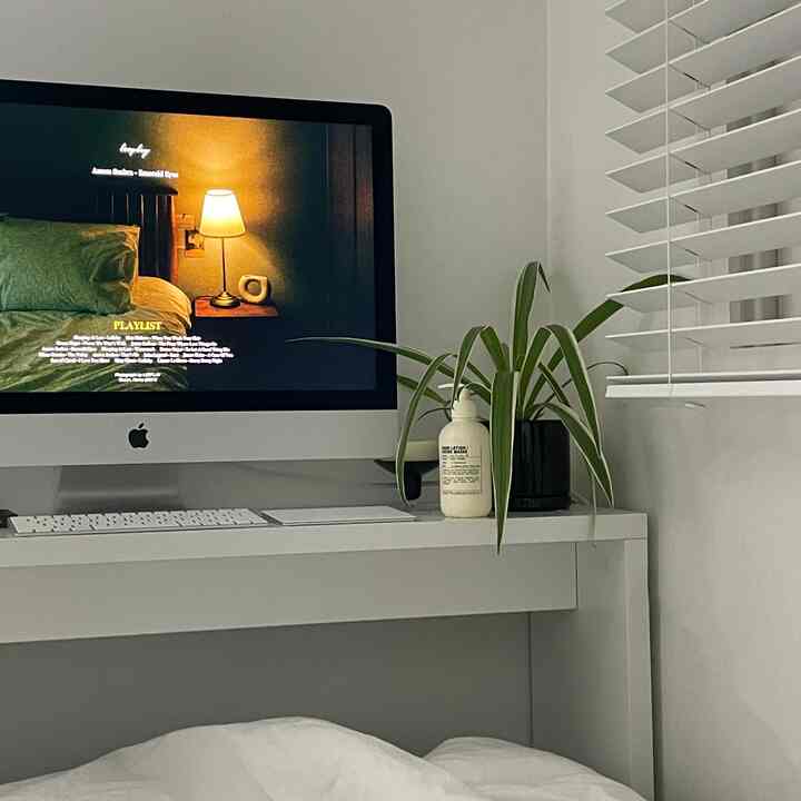 白を基調とした寝室のホームオフィス、白いデスクにiMacと緑の植物が置かれた落ち着いた雰囲気のインテリア