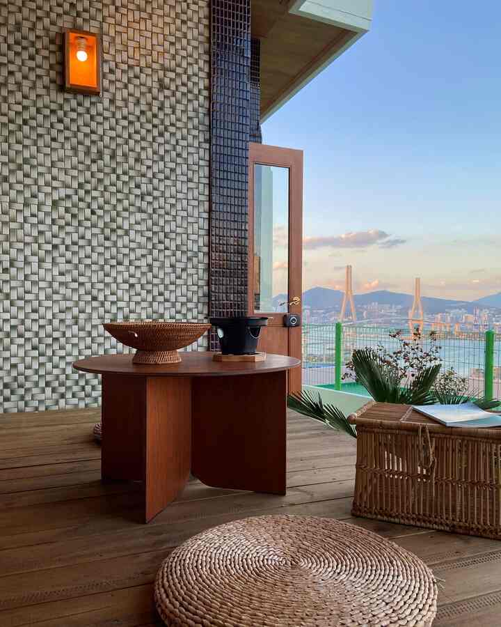 茶色の木目調ベランダ空間、丸いラタンバスケットと木製座卓が配置された自然な雰囲気のインテリア